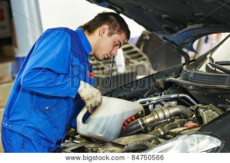 auto mechanic technician replacing and pouring motor oil into automobile engine at maintenance repair service station