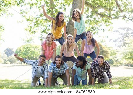 Happy friends in the park making human pyramid on a sunny day