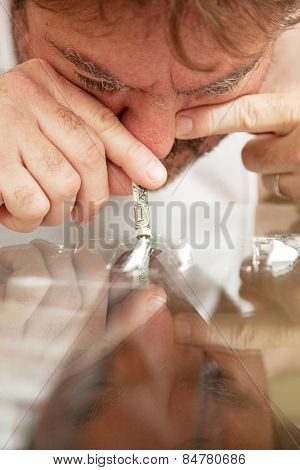 Man snorting cocaine off of his glass coffee table with a rolled up dollar bill.   