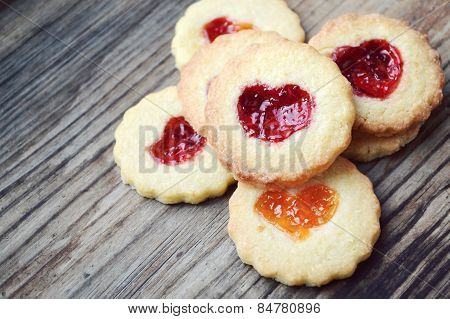 Homemade cookies with heart shaped jam on wooden table