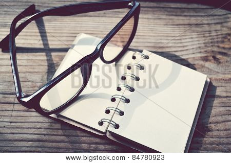 An empty retro spiral notebook with old paper and reading glasses