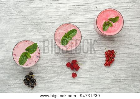 Fresh milk, currant, raspberry and red currant drinks on wodeen table, assorted protein cocktails wi