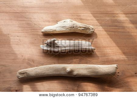 Three drift wood on a rustic wooden board. with natural window like lighting.