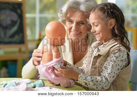 Portrait of grandmother and child play with baby doll