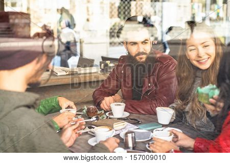 Group of friends enjoying cappuccino and latte macchiato together in a coffee shop - View through glass with reflections - Caffeine addiction concept - Focus on bearded man - Warm vintage filter