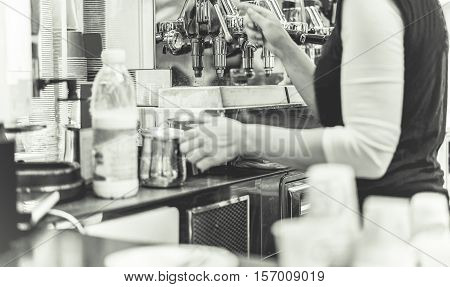 Barman working in coffee shop - Woman making bio organic coffee for customer - Caffeine addiction in morning time - Focus on first left exit of coffee machine - Black and white editing - Warm filter