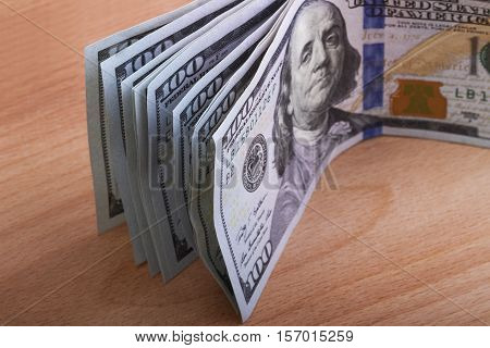 several hundred dollar bills on a wooden table