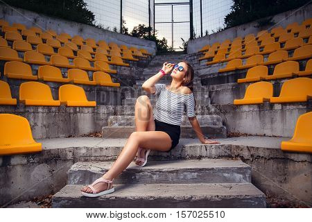 Fashionable Woman With Round Glasses Sitting On The Steps