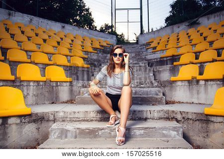 Fashionable Woman With Round Glasses Sitting On The Steps