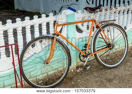 Orange bicycle stands at the green fence