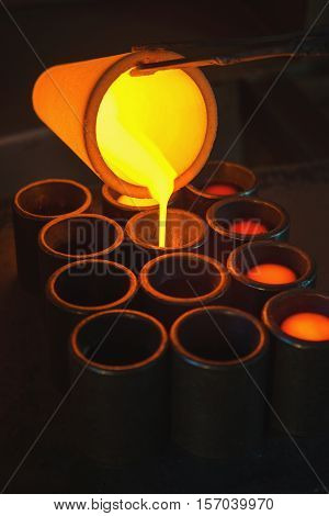 Pouring melted gold in the metal form at a factory