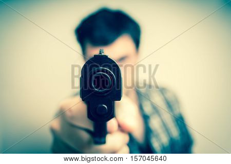 Crazy young man aiming automatic gun at you - retro style