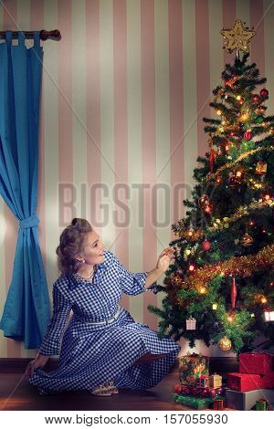portrait of nice young woman hanging around christmas tree on x-mas eve