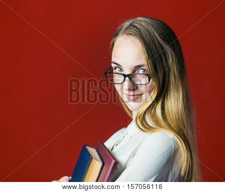 attractive happy smiling student blonde girl in white shirt with books on red background, student concept