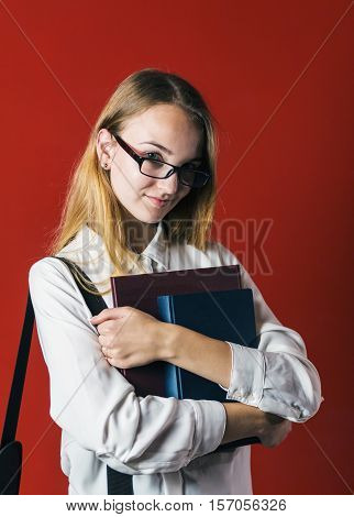 attractive happy smiling student blonde girl in white shirt with books on red background, student concept