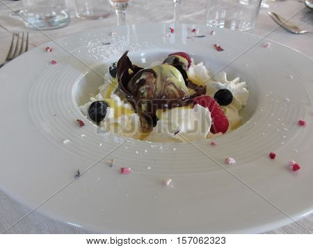 Melted chocolate ball with zabaglione cream whipped cream raspberries and blueberries
