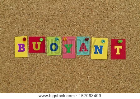 Buoyant word written on colorful sticky notes pinned on cork board.