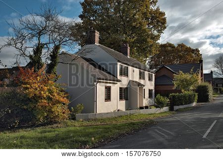 View on an entrance area of english house. White residential building near autumn trees