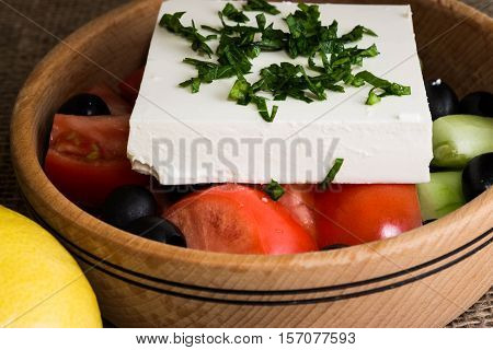 Greek salad with feta cheese and vegetables on wooden plate