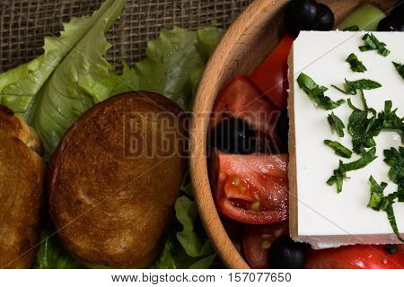 Greek salad with feta cheese and vegetables on wooden plate
