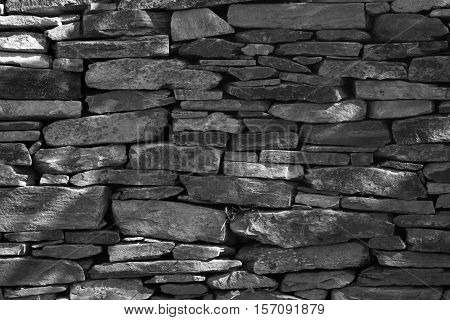 Stone wall built from stones and rocks of different sizes in black and white.