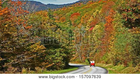 an antique car ambles down the Blue Ridge Parkway during autumn foliage season