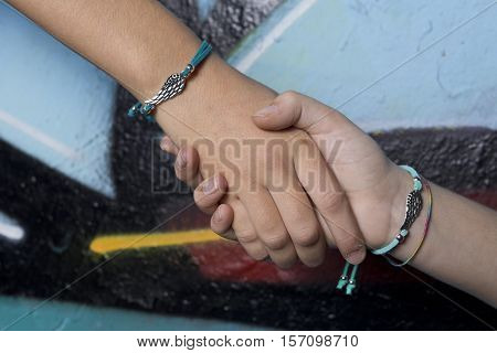 Elche, Spain. October 23, 2016: Two hands of friends caught on a background painted with graffiti.
