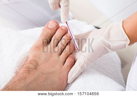 Close-up Of A Beautician Hand Filling Person's Nail In Salon