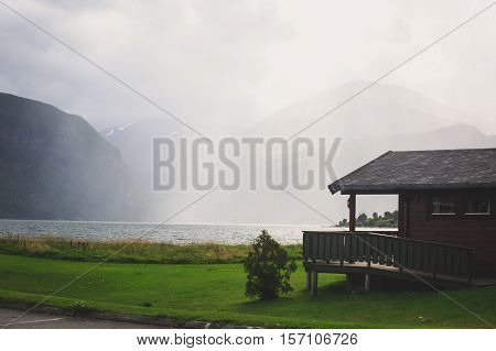 Beautiful landscape with classical scandinavian camping cottage wooden house cabin chalet hut, on a lake shore coastline, in sunny summer day in Norway