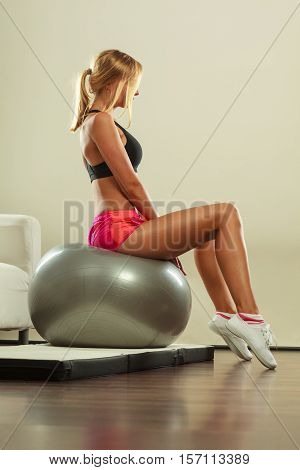 Sport training gym and lifestyle concept. Young attractive slim woman in sportswear doing fitness exercises with fit ball at home