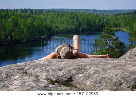 a woman laying on cliff an relaxing above the lake Yastrebinoye Priozersky district in Leningrad region Russia
