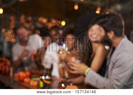 Young adults socialising at a party in a bar, defocussed