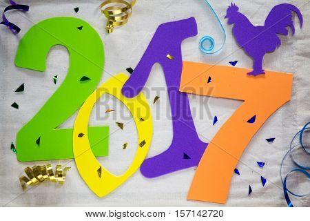 New 2017 year of the rooster. Colorful figures on the background of bright tinsel and ribbons