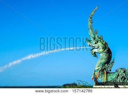 Naga statue spray water to the sea with blue sky background