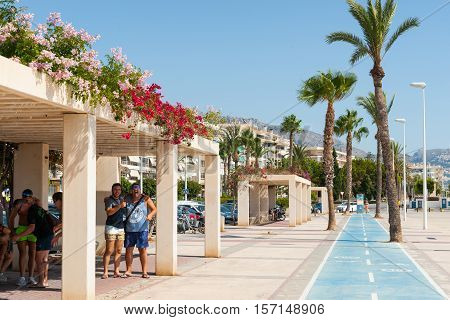Altea, Spain - September 7, 2016: Tourists enjoying themselves  shade shelter on esplanade cycleway along waterfront in Altea, Spain.