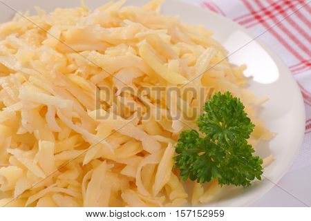 plate of grated raw potatoes on checkered dishtowel - close up