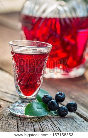 Homemade Liqueur With Alcohol And Chokeberries On Old Wooden Table