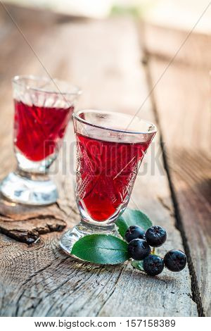 Fresh Liqueur With Chokeberries And Alcohol On Old Wooden Table
