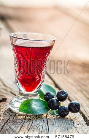 Fresh Liqueur With Alcohol And Chokeberries On Old Wooden Table