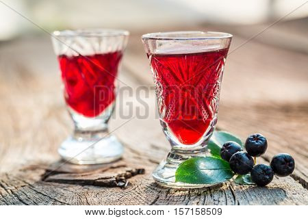 Sweet Liqueur With Chokeberries And Alcohol On Old Wooden Table