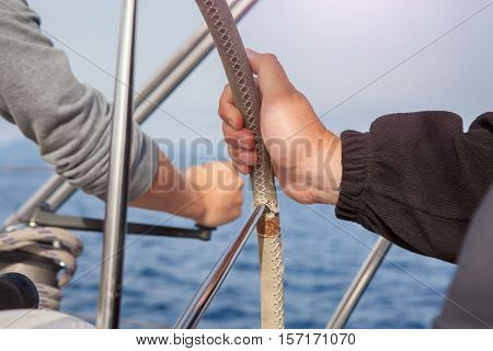 man hand holding a sailing vessel wheel.the sea in the background