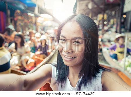 Thai woman at the floating market taking selfie with camera