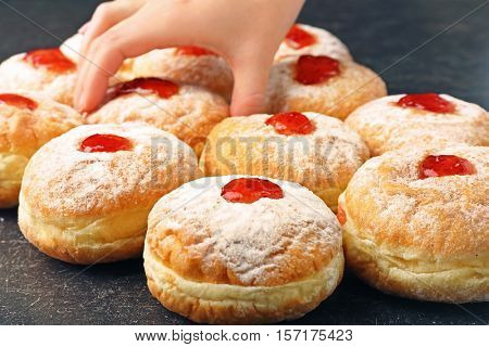 Female hand taking tasty donut from dark table. Hanukkah celebration concept