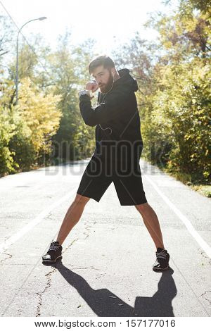 Athletic runner warming up in park. front view