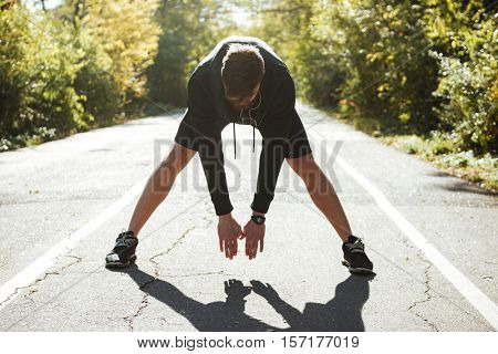 Young runner warming up in park. front view