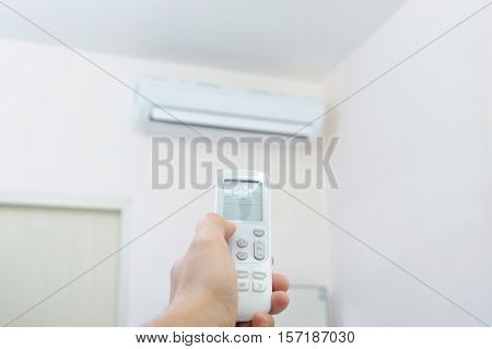Hand with remote control directed on the conditioner