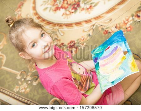 a cheerful smiling girl holding a bright colorful picture painted colors and crayons in kindergarten - Moscow Russia - February 4 2016