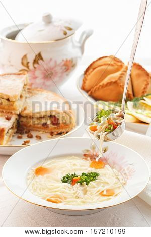 Traditional Tatar holiday table. Tokmach - noodle soup with chicken. Triangles - meat pies and sweet cake. Selective focus
