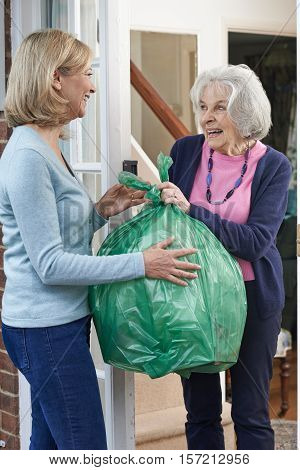 Woman Taking Out Trash For Elderly Neighbour