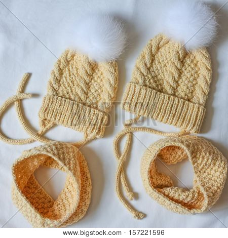 Two Yellow Sets Of Caps With A Fluffy Bobble And Snood